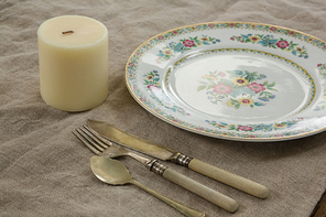 Close-up of floral pattern plate with cutlery set and candle