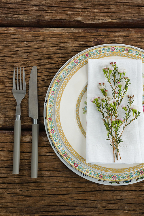Overhead of flora and napkin arranged on plate with cutlery