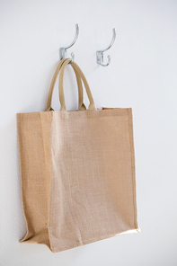 Close-up bag hanging on hook against white wall
