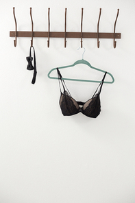Lingerie and bow tie hanging on hook against white wall