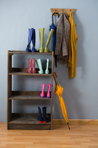 Wellington boots, umbrella and blazer on hook against wall