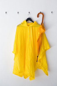 Raincoat and umbrella hanging on hook against wall