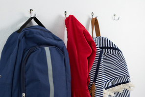 Close-up of schoolbags and hoodie hanging on hook
