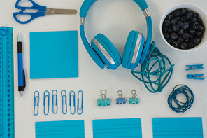 Overhead of headphones, blueberries and stationery on white background