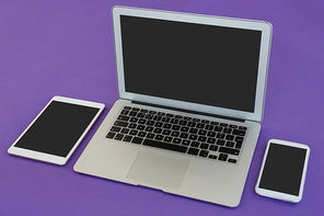 Close-up of laptop, mobile phone and digital tablet on purple background