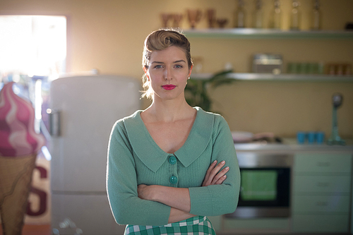 Portrait of waitress standing with arms crossed in restaurant