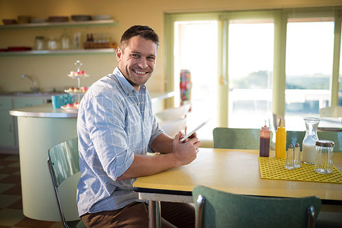 Smiling man using digital tablet in restaurant