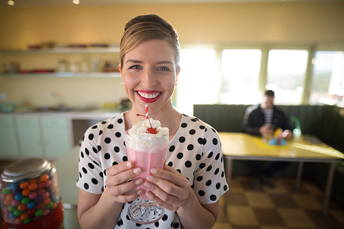 Young woman having milkshake in restaurant