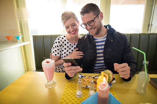 Young couple using mobile phone in restaurant