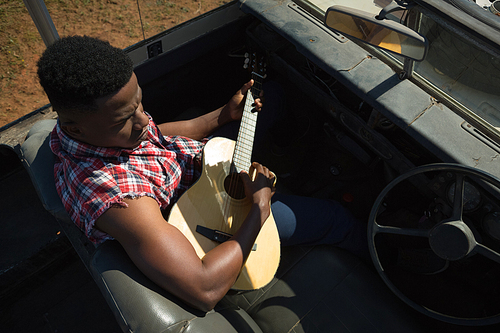 Man playing guitar in car on a sunny day