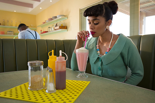 Young woman having milkshake at restaurant