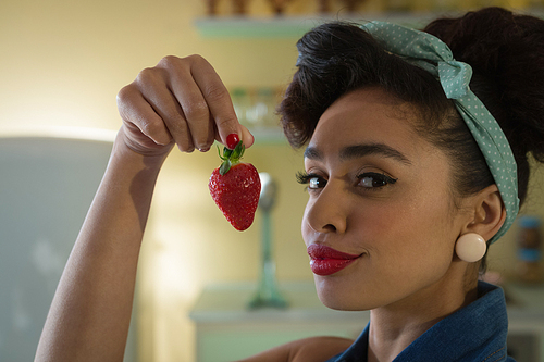 Portrait of woman having a strawberry at home