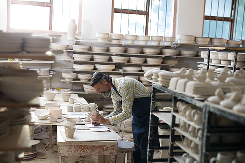 Male potter checking bowl in pottery workshop