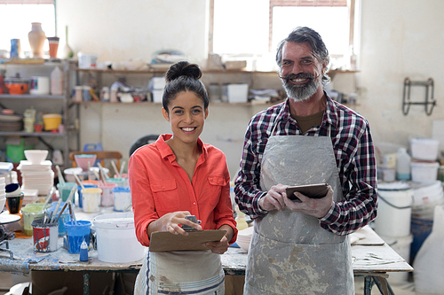 Portrait of male and female potter standing in workshop