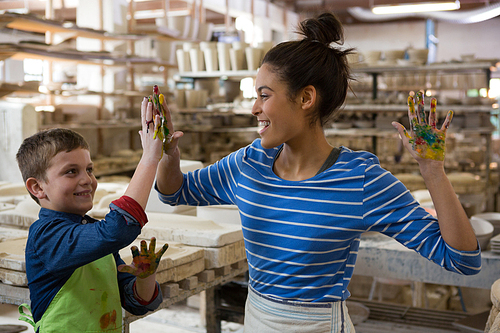 Mother and son giving high five to each other at pottery shop