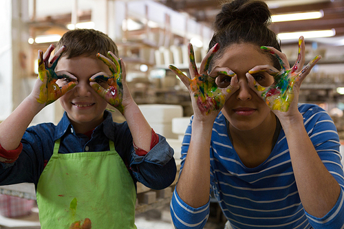 Happy mother and son gesturing in pottery workshop