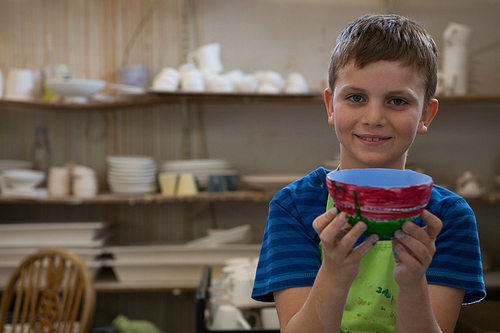 Portrait of boy holding a panted pot in pottery workshop