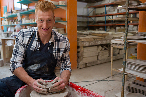 Portrait of male potter making a pot in pottery workshop