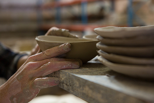 Male potters hand examining a bowl in pottery workshop