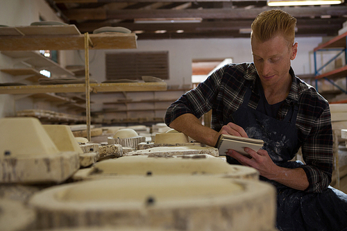 Male potter writing on a diary in pottery workshop