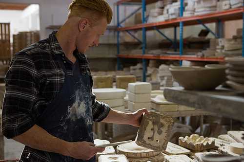 Male potter examining a clay in pottery workshop