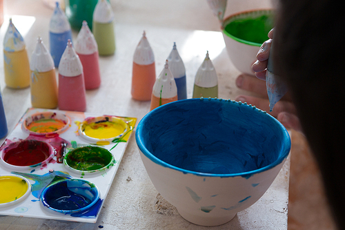 Girl decorating bowl with paint in pottery workshop