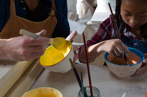 Male potter and girl painting bowl in pottery workshop