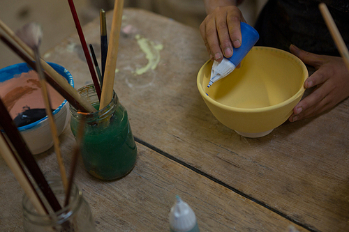 Mid section of girl painting bowl in pottery workshop