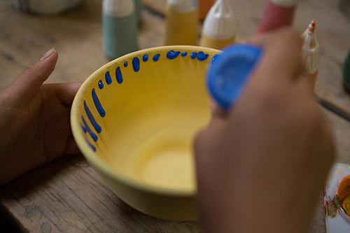 Hands of girl painting bowl in pottery workshop