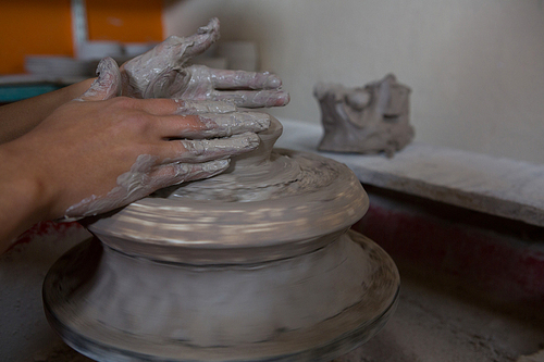 Hands of female potter molding a clay in pottery workshop
