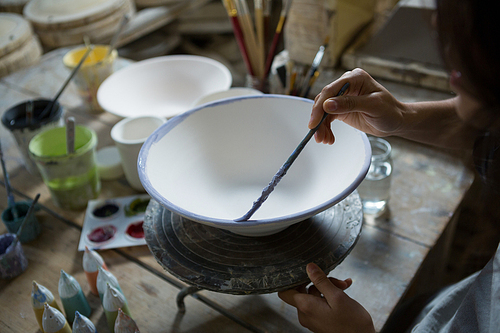 Female potter painting bowl in pottery workshop