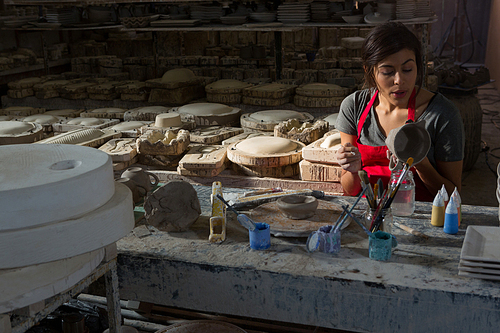 Female potter carving mug in pottery workshop