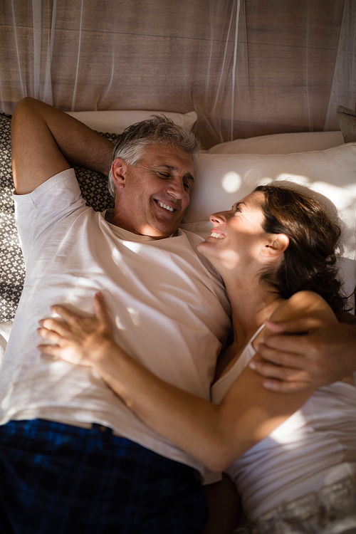 Happy couple relaxing in canopy bed during morning