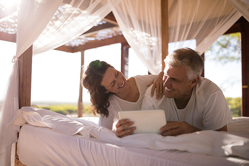 Happy couple using digital tablet on bed during morning