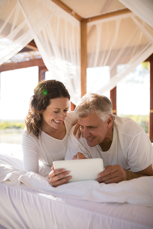 Happy couple using digital tablet on bed during morning