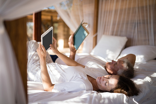 Couple relaxing on canopy bed during morning