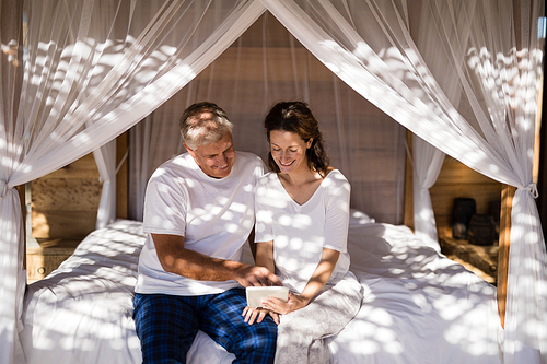 Happy couple using digital tablet on bed during morning