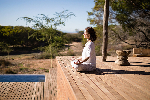 Woman practicing yoga on wooden plank on a sunny day