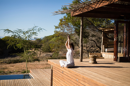 Woman practicing yoga on wooden plank on a sunny day