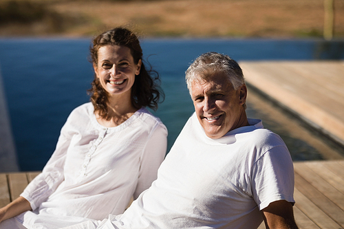 Portrait of happy couple relaxing on wooden plank on a sunny day