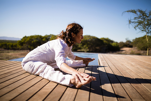 Woman practicing yoga on wooden plank on a sunny day