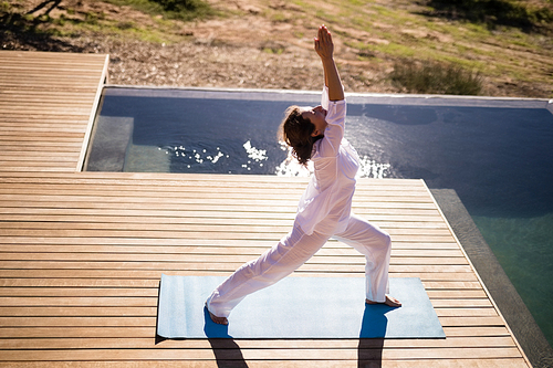 Woman practicing yoga on at poolside on a sunny day