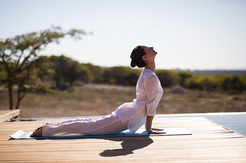 Woman practicing yoga on at poolside on a sunny day