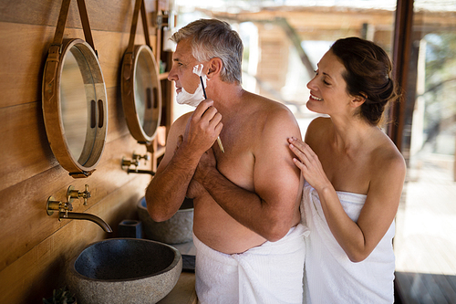 Smiling woman looking while man shaving his beard during safari vacation