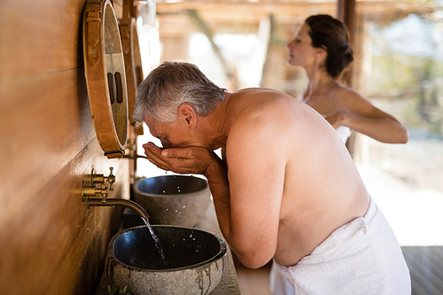 Man washing face from water in cottage during safari vacation