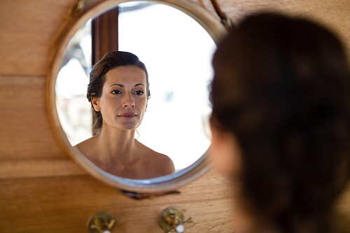 Woman looking at mirror in cottage during safari vacation