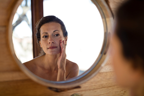 Woman looking at mirror in cottage during safari vacation