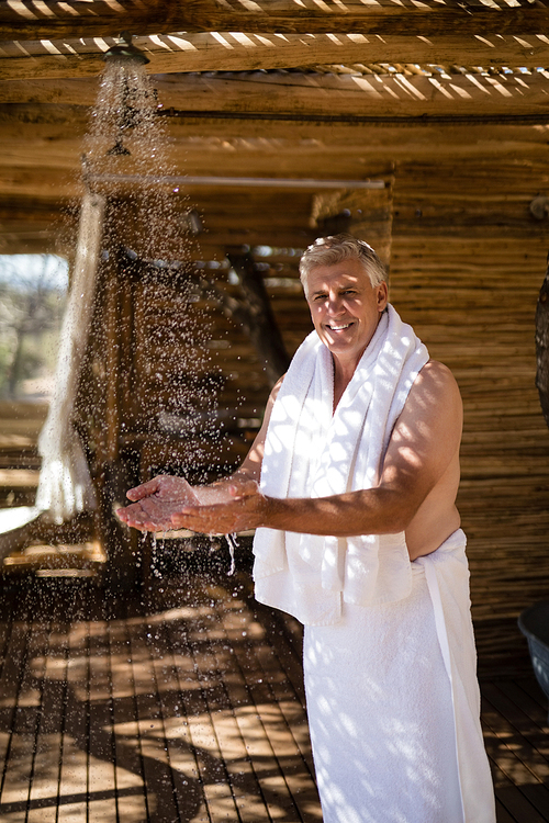 Portrait of man washing hands from shower in cottage during safari vacation