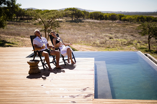 Couple relaxing while having a glass of drink near poolside