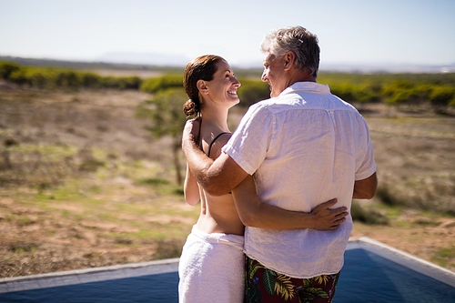 Smiling couple embracing near poolside during safari vacation